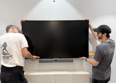 Two nesevo technicians mounting a display above a video bar in a meeting room